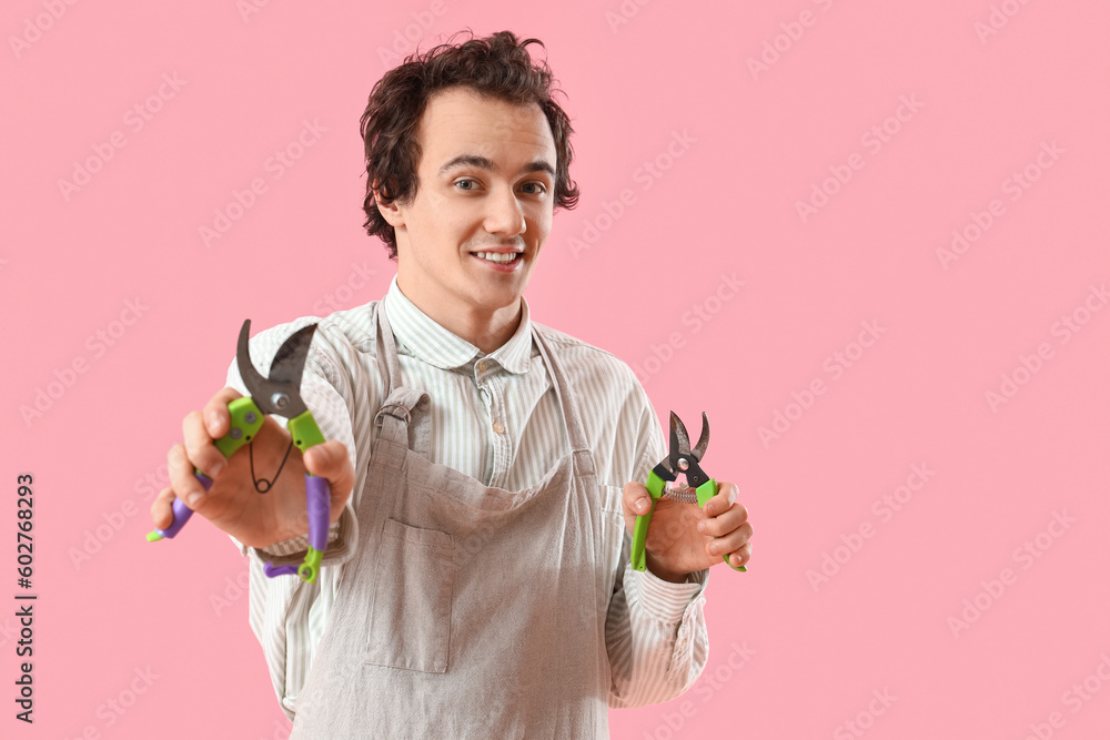 Male gardener with secateurs on pink background