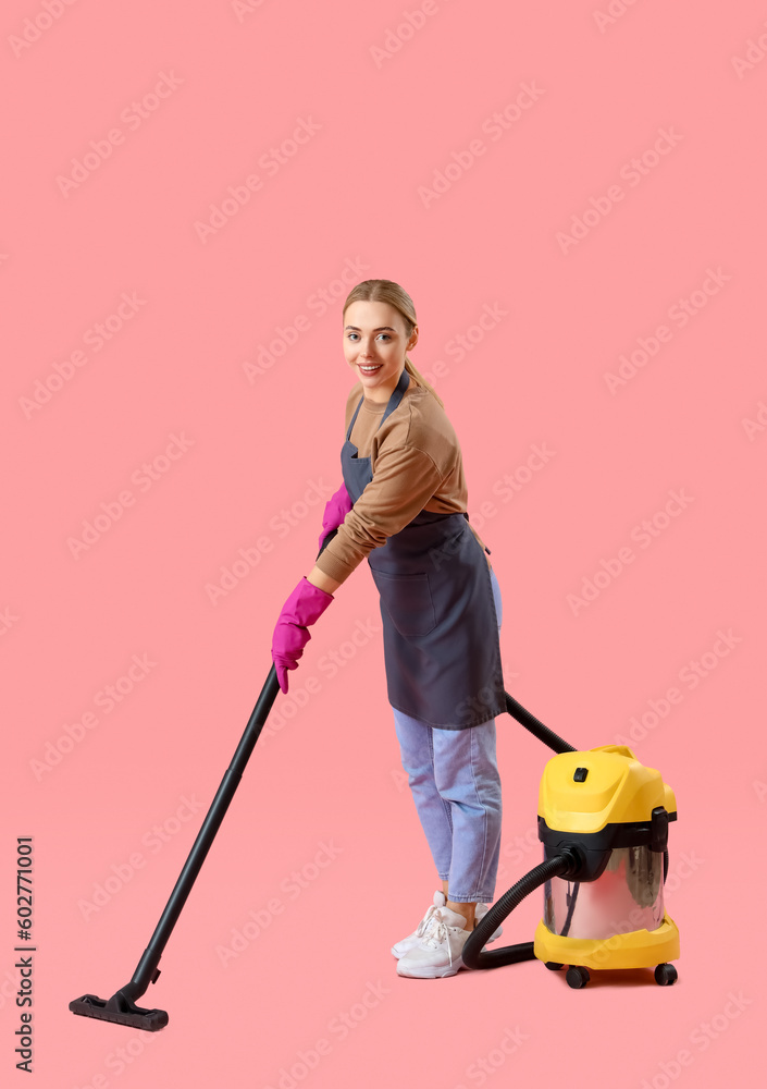 Young woman with vacuum cleaner on pink background