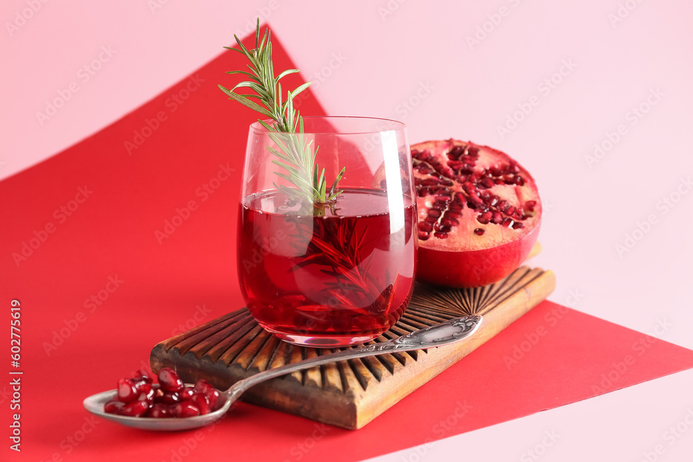 Board with glass of fresh pomegranate juice on colorful background