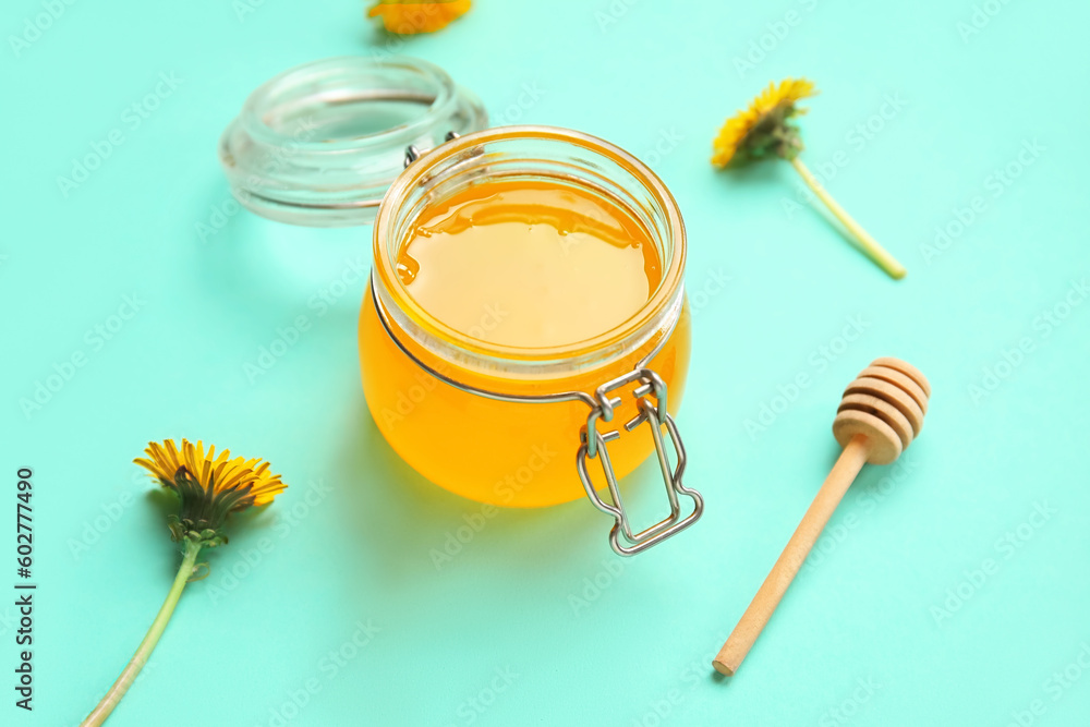 Jar with dandelion honey on turquoise background