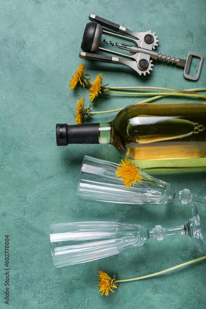 Bottle and glasses of dandelion wine on green background