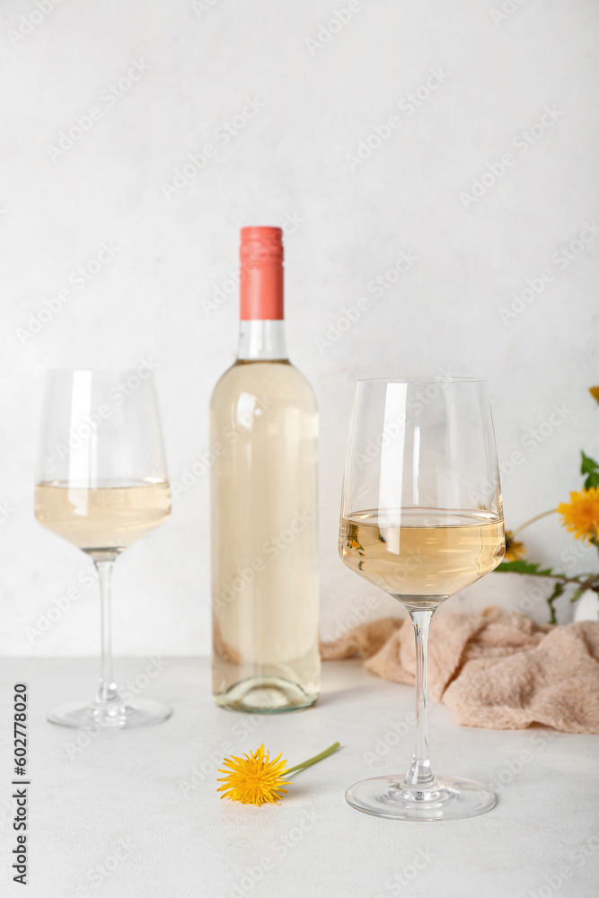 Bottle and glasses of dandelion wine on white table