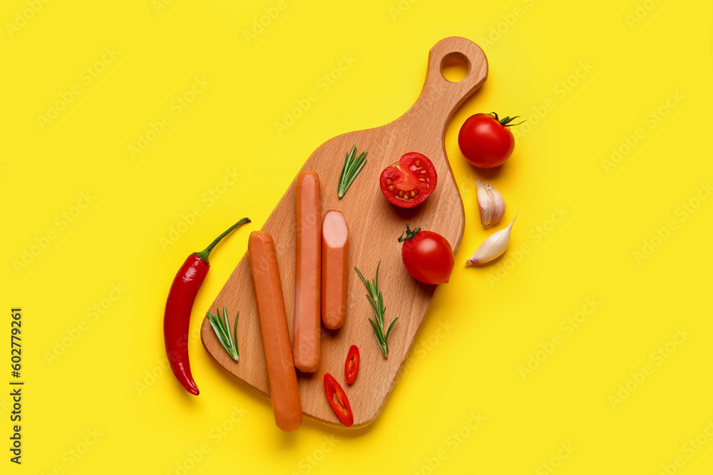 Board of tasty sausages with chilli and tomatoes on yellow background