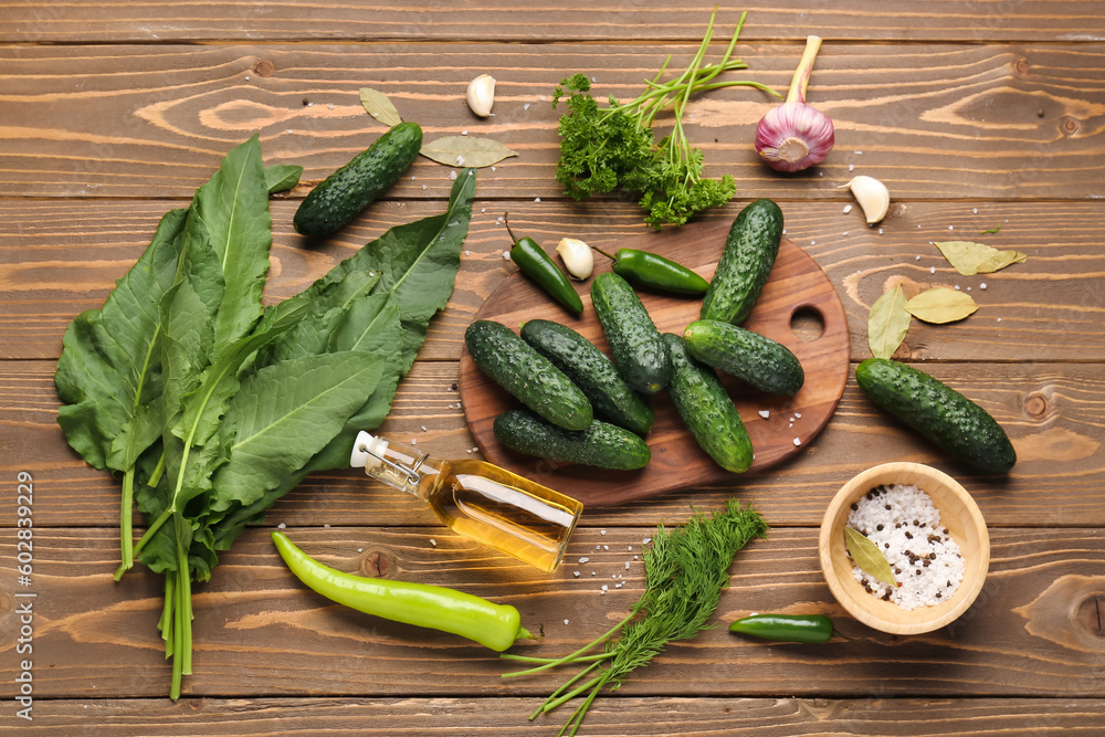 Board with fresh cucumbers and ingredients for preservation on wooden background