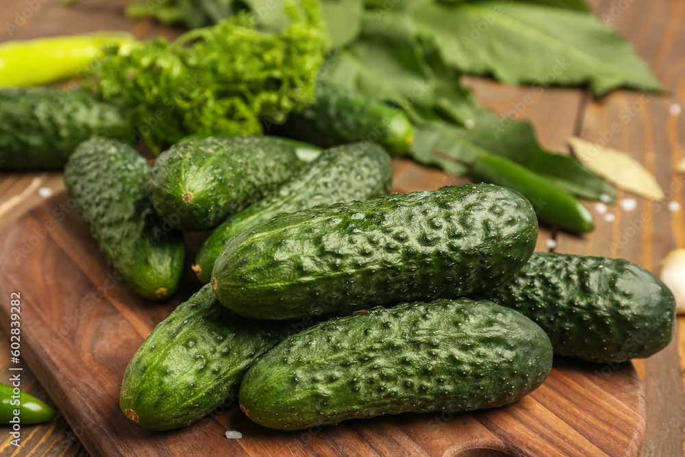 Wooden board with fresh cucumbers for preservation on table, closeup