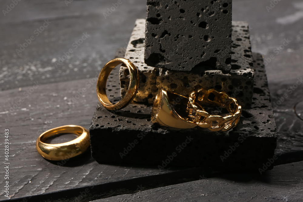 Decorative podium with beautiful rings on black wooden background