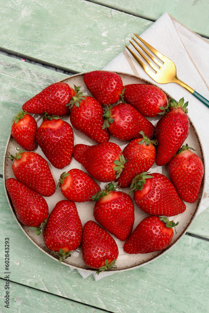 Plate with fresh strawberries on green wooden background