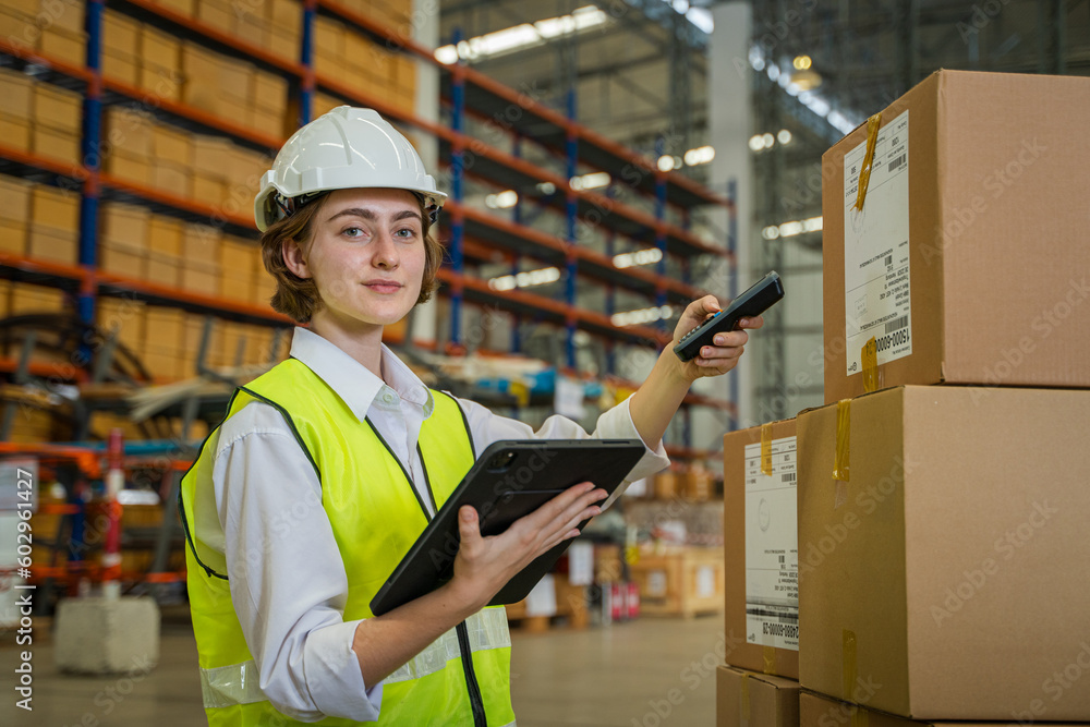 Warehouse worker checking and loading or unloading boxes in a large distribution warehouse.