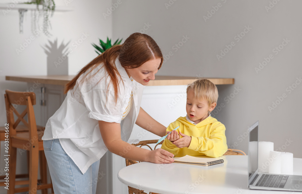 Mother and her little son drawing in notebook at home