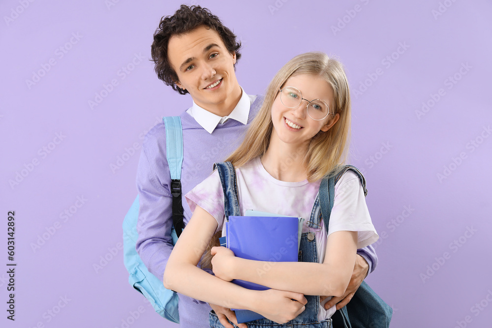 Teenage couple with books on lilac background