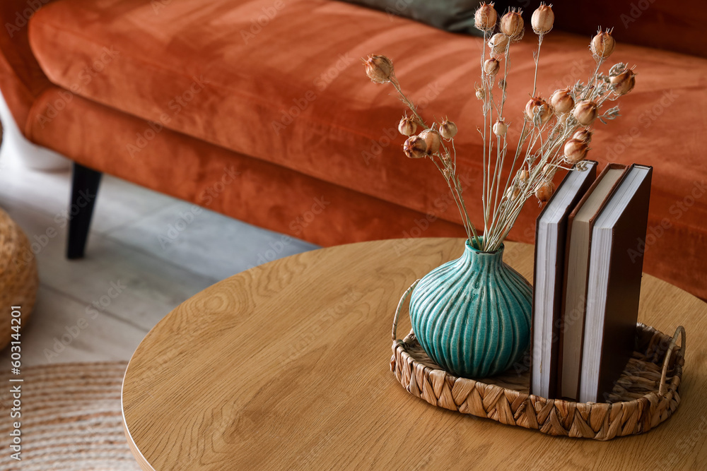 Vase with dried flowers and books on coffee table in living room, closeup