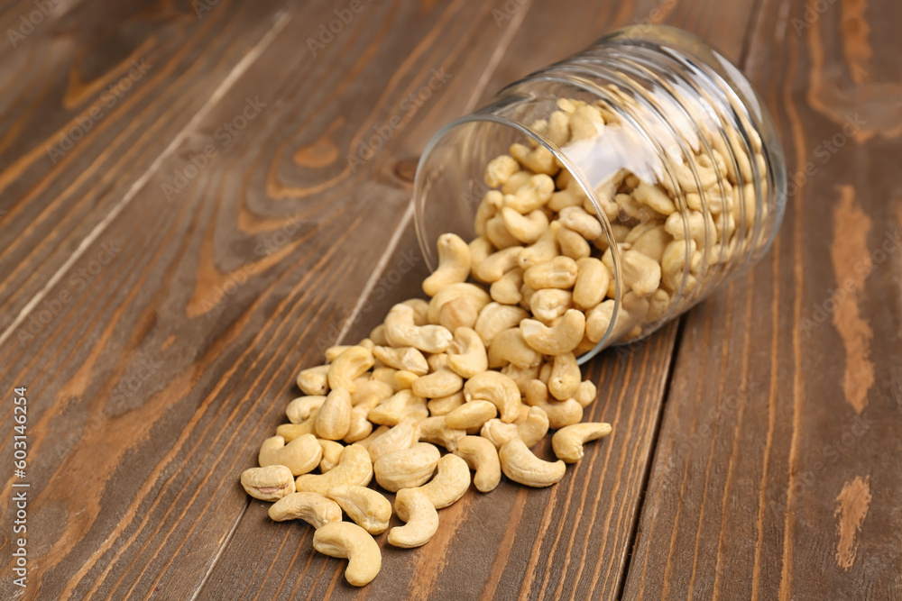 Jar with tasty cashew nuts on wooden background