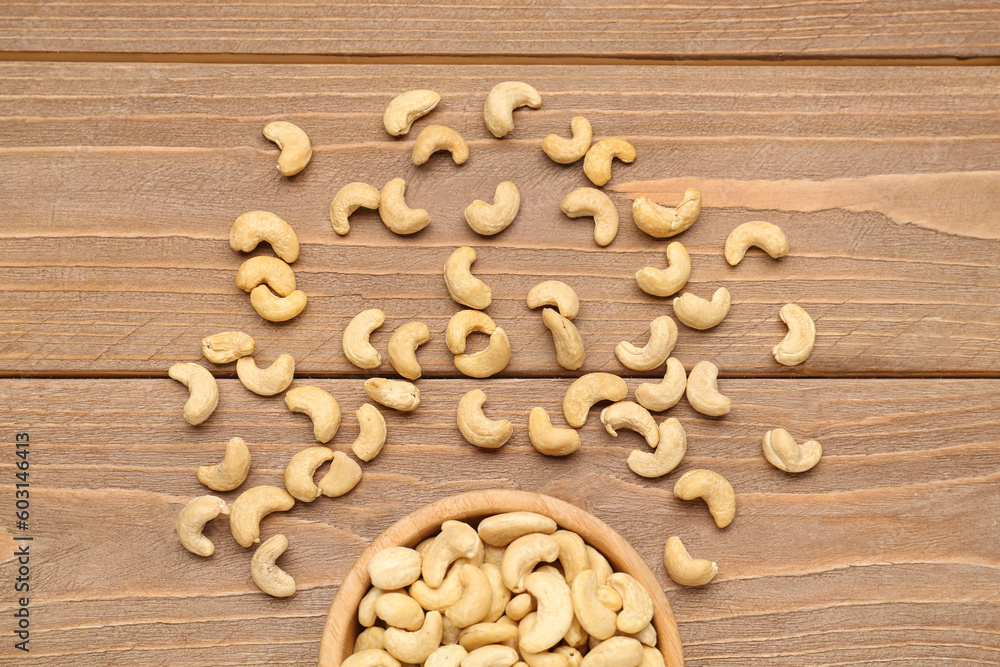 Bowl with tasty cashew nuts on wooden background