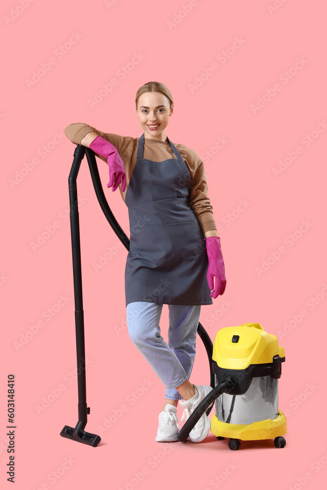 Young woman with vacuum cleaner on pink background