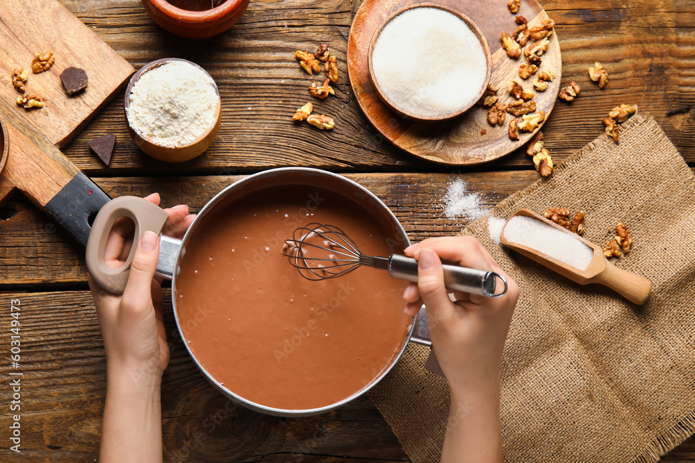 Woman preparing dough for chocolate brownie on wooden background