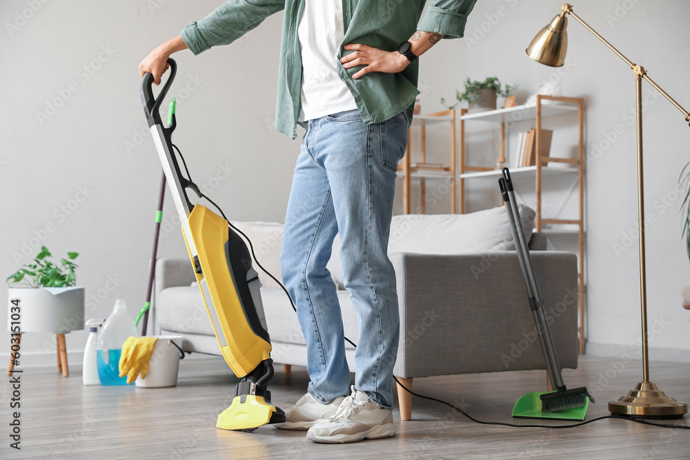 Young man with vacuum cleaner at home