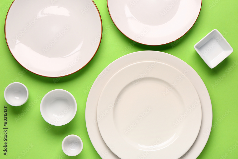 Composition with clean plates and bowls on green background