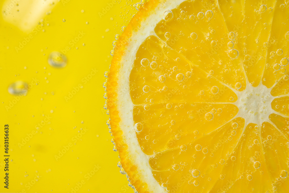 Lemon slice in water with bubbles on yellow background