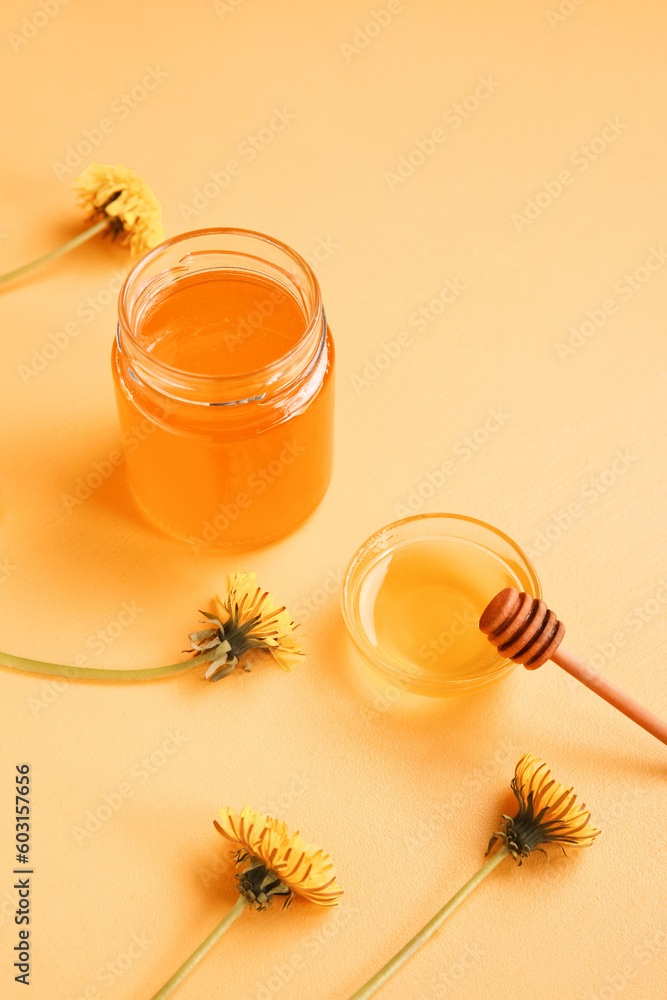 Jar and bowl with dandelion honey on orange background