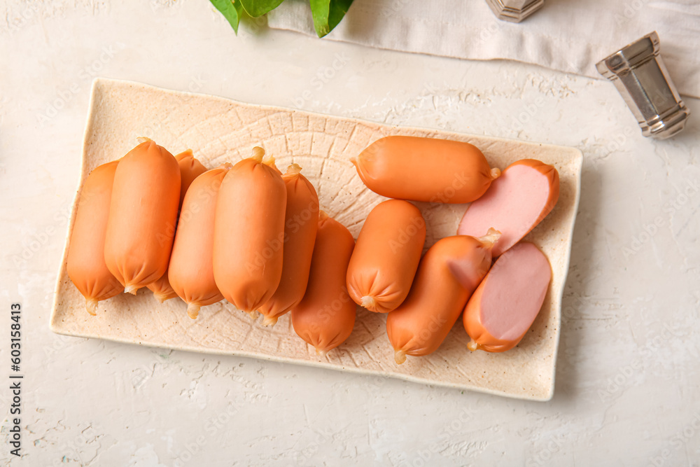 Plate of tasty boiled sausages on white background