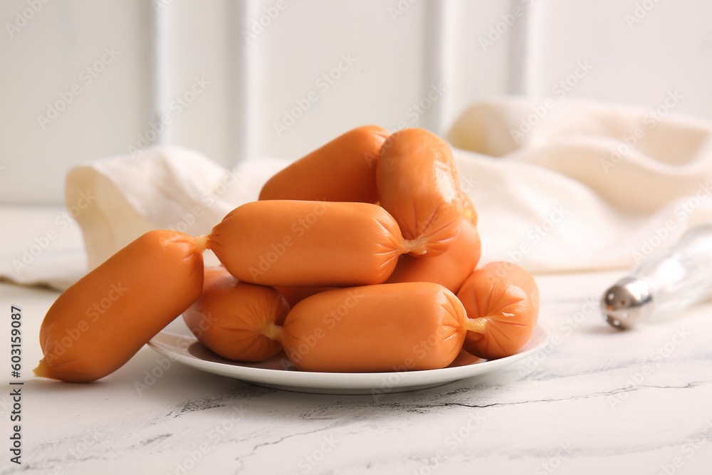 Plate of tasty boiled sausages on white table