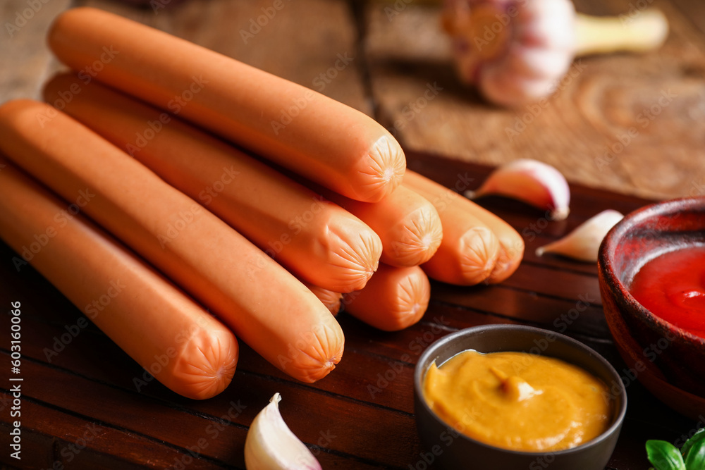 Board of tasty sausages with mayonnaise and mustard on wooden background