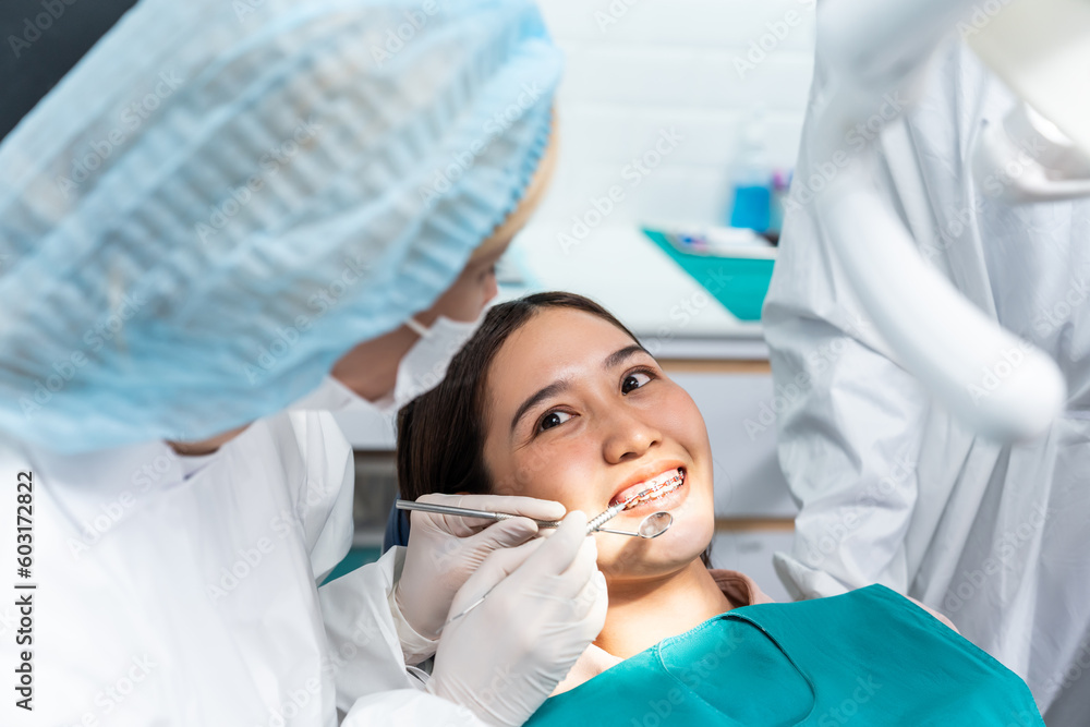 Caucasian dentist examine tooth for young girl at dental health clinic.