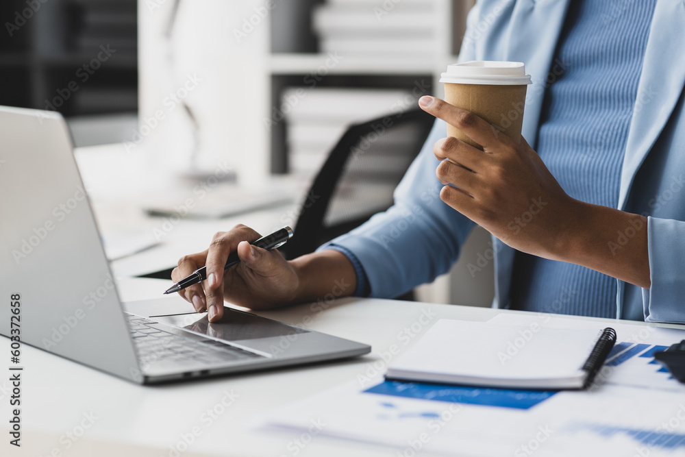 Businesswoman working with laptop and financial documents on desk, financial and investment data ana