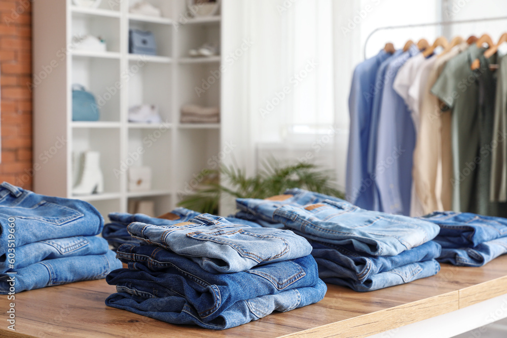 Table with stylish jeans pants in modern boutique, closeup