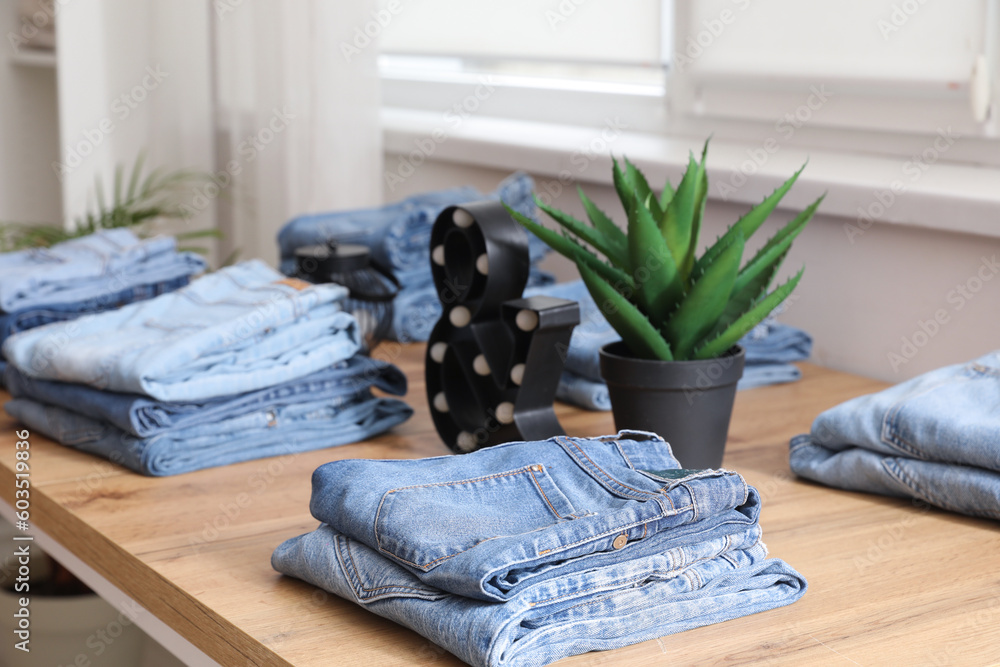 Table with stylish jeans pants in modern boutique, closeup