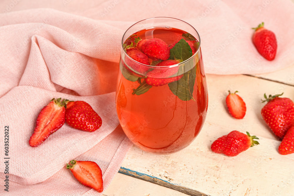 Glass of tasty strawberry juice on white table