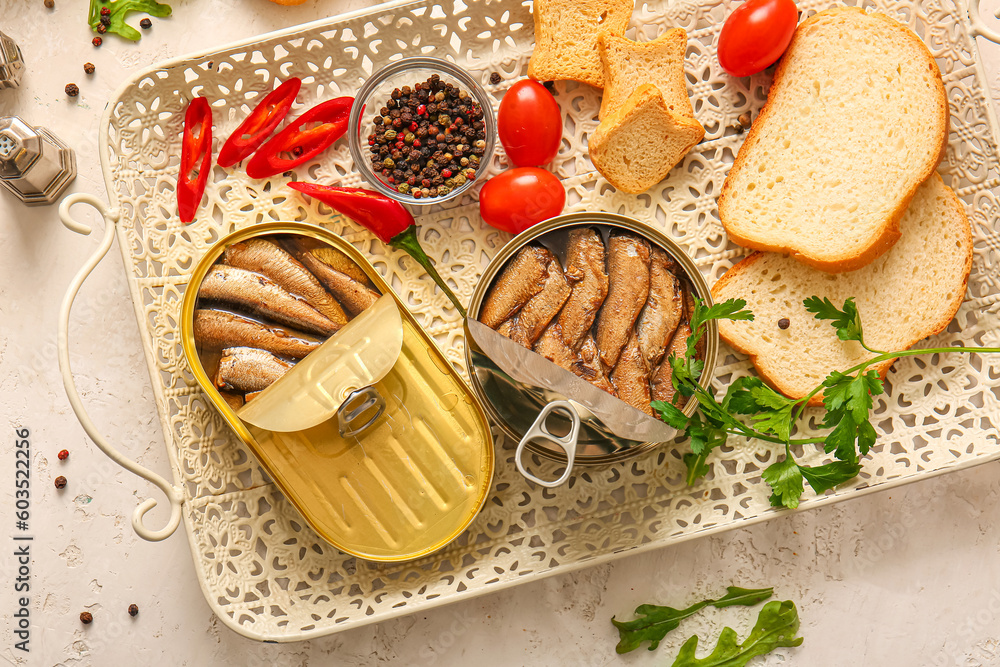 Tray of canned smoked sprats with bread and chilli on white table