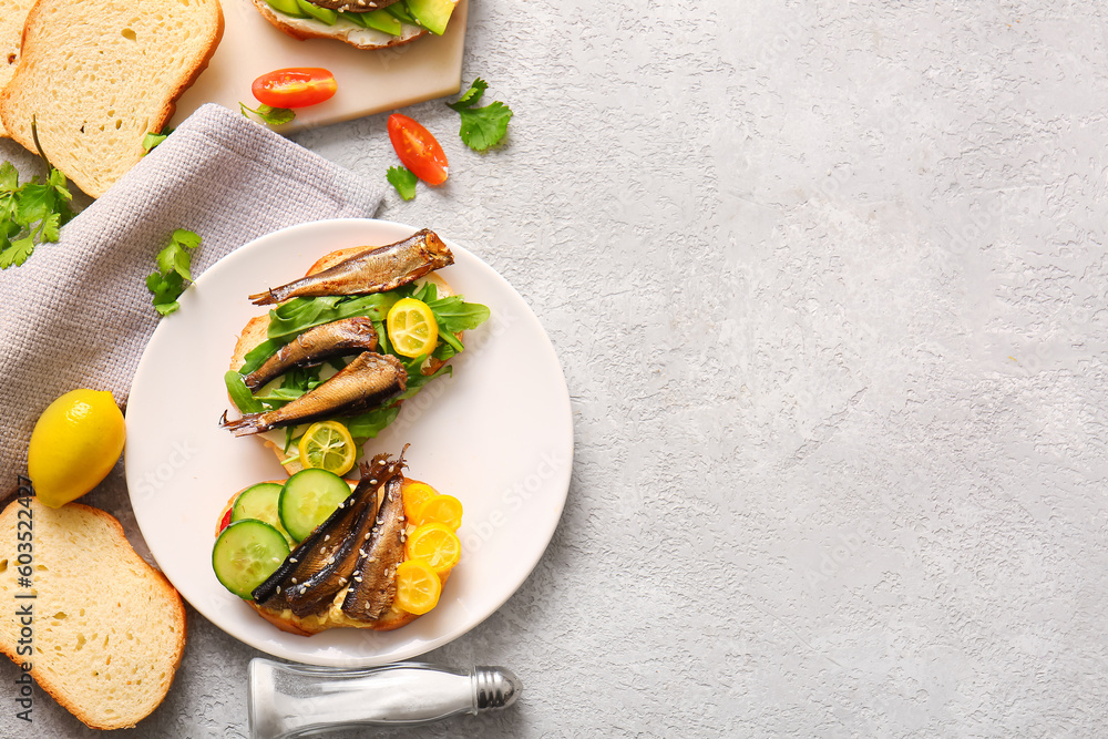 Plate of tasty sandwiches with canned smoked sprats on grey background