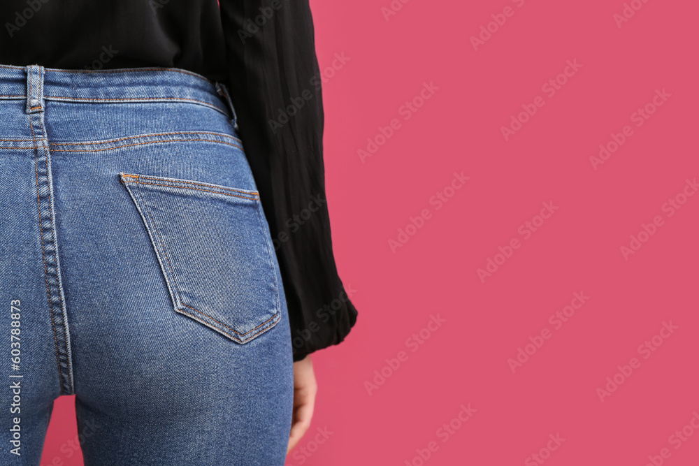 Young woman in stylish jeans on red background, back view