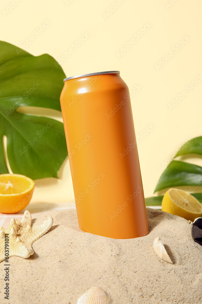 Can of soda with seashells and citrus fruits on sand, closeup