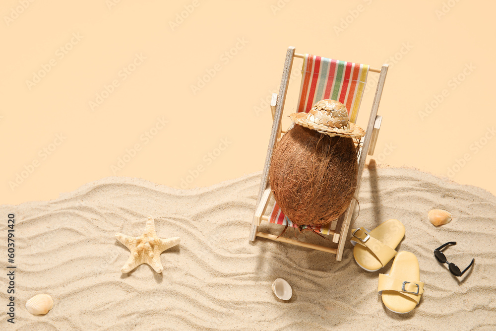 Deck chair with coconut, beach accessories and sand on beige background