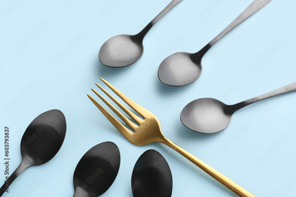 Stylish spoons and fork on blue background