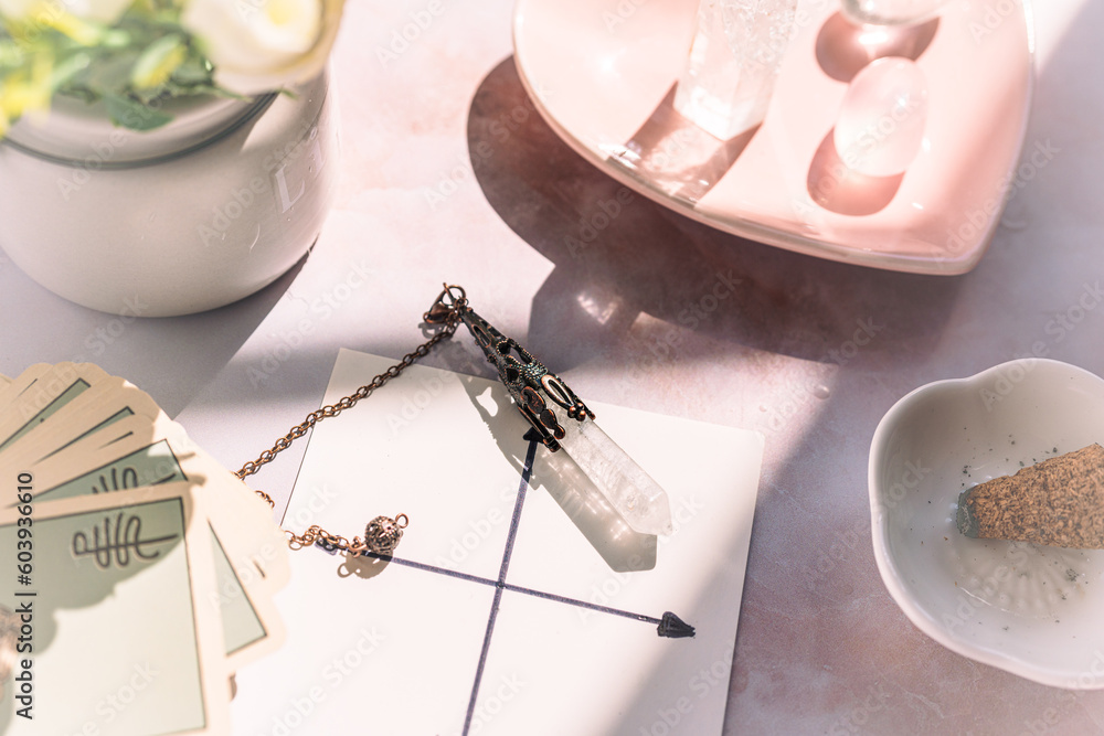 Gemstones for esoteric spiritual practice. Rock crystal pendulum on the table. Divination with a pen