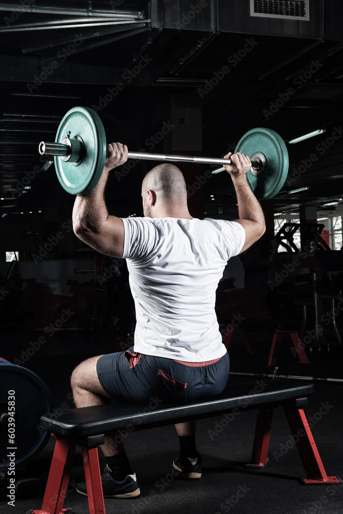 Male athlete lifts the barbell