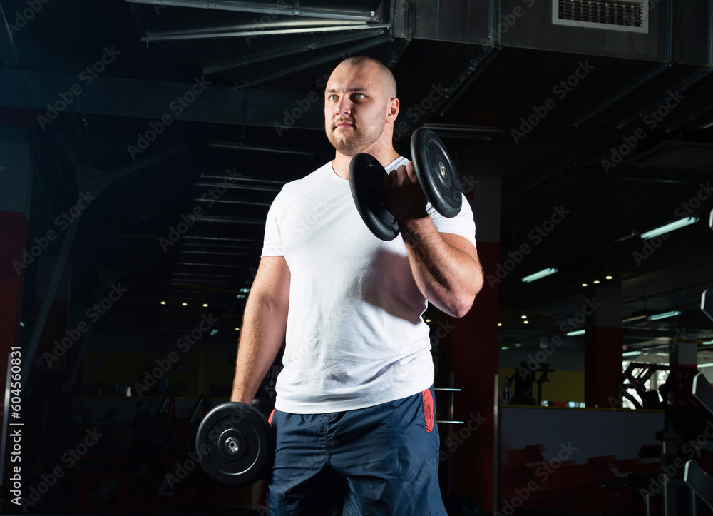 Male bodybuilder engaged with dumbbells in the gym