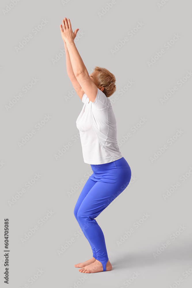 Sporty mature woman practicing yoga on light background