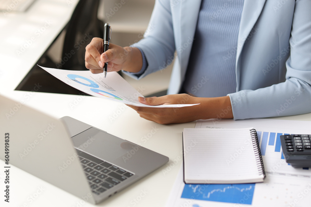 Businesswoman working with laptop and financial documents on desk, financial and investment data ana