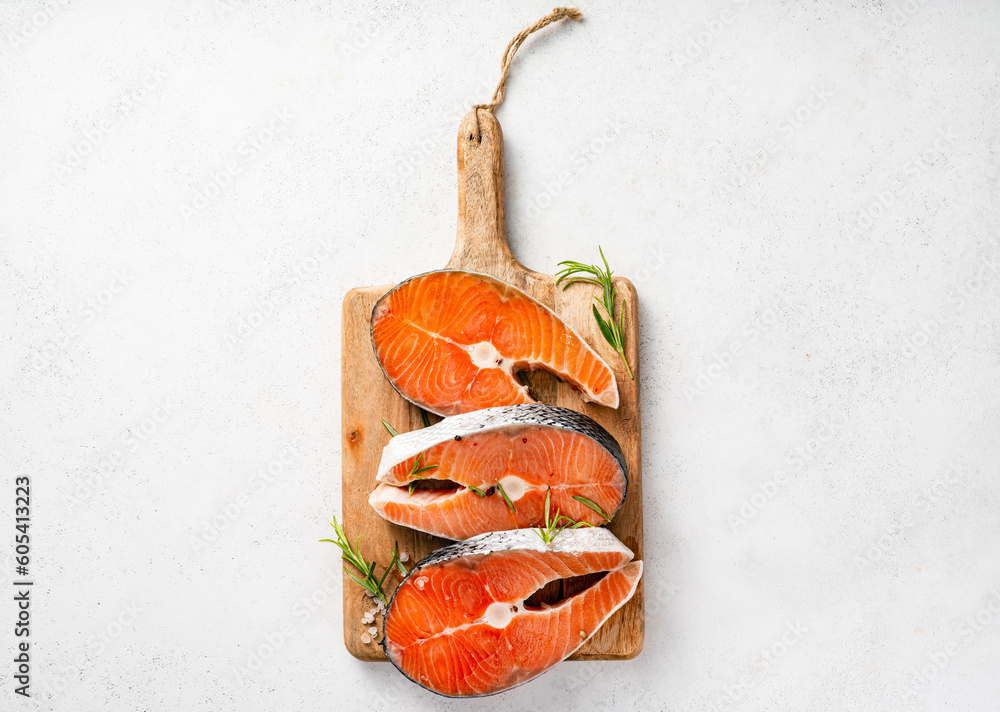 Fresh raw salmon steaks on wooden board. Top view of fish on white background.