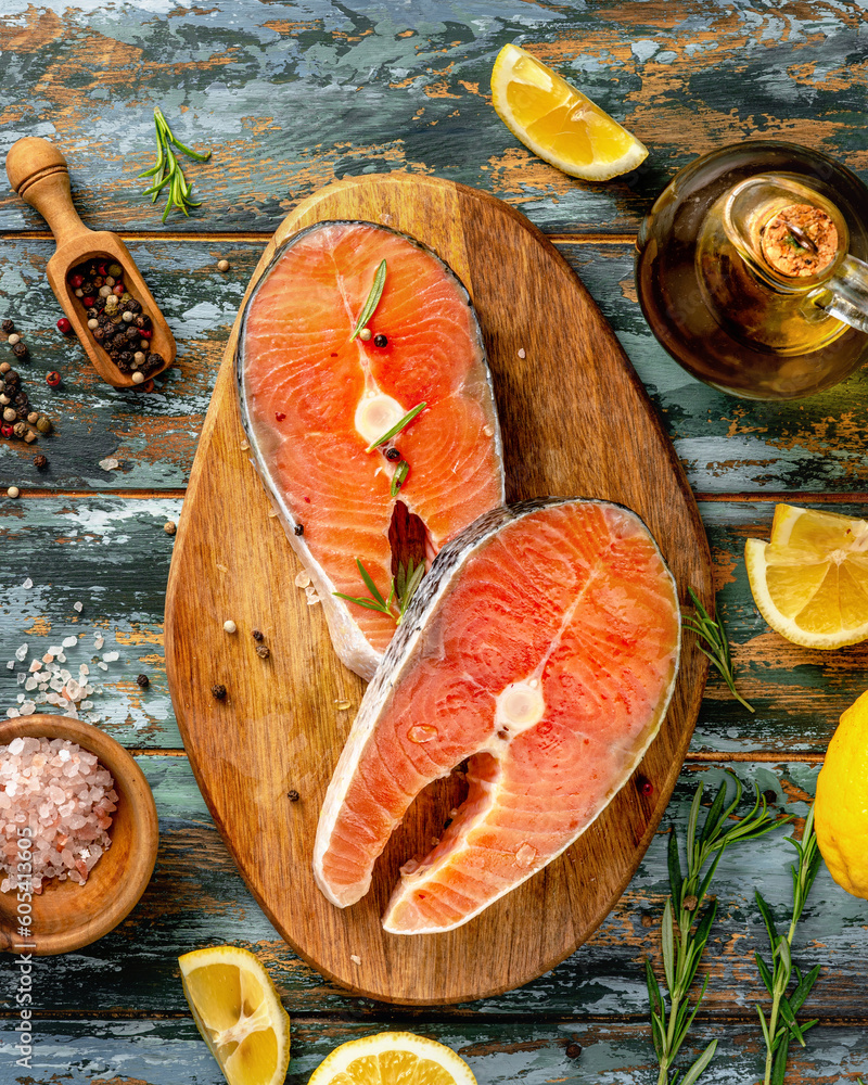 Two fresh fish salmon pieces. Raw Salmon steaks with lemons and spices on wooden board.