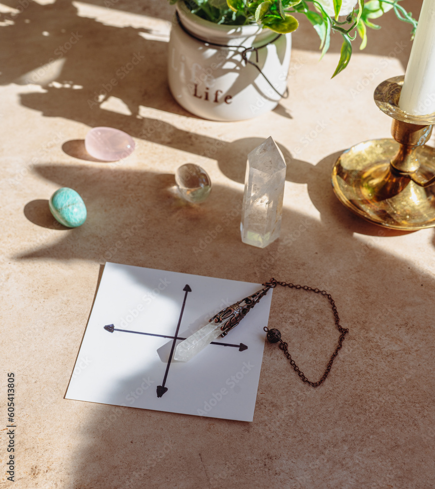 Gemstones for esoteric spiritual practice. Rock crystal pendulum on the table. Divination with a pen