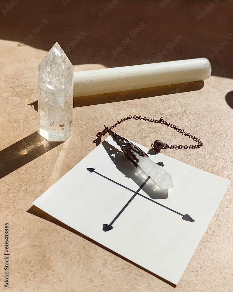 Gemstones for esoteric spiritual practice. Rock crystal pendulum on the table. Divination with a pen