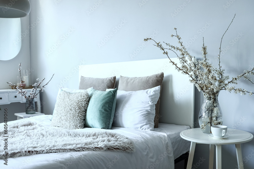 Vase with blossoming tree branches on bedside table