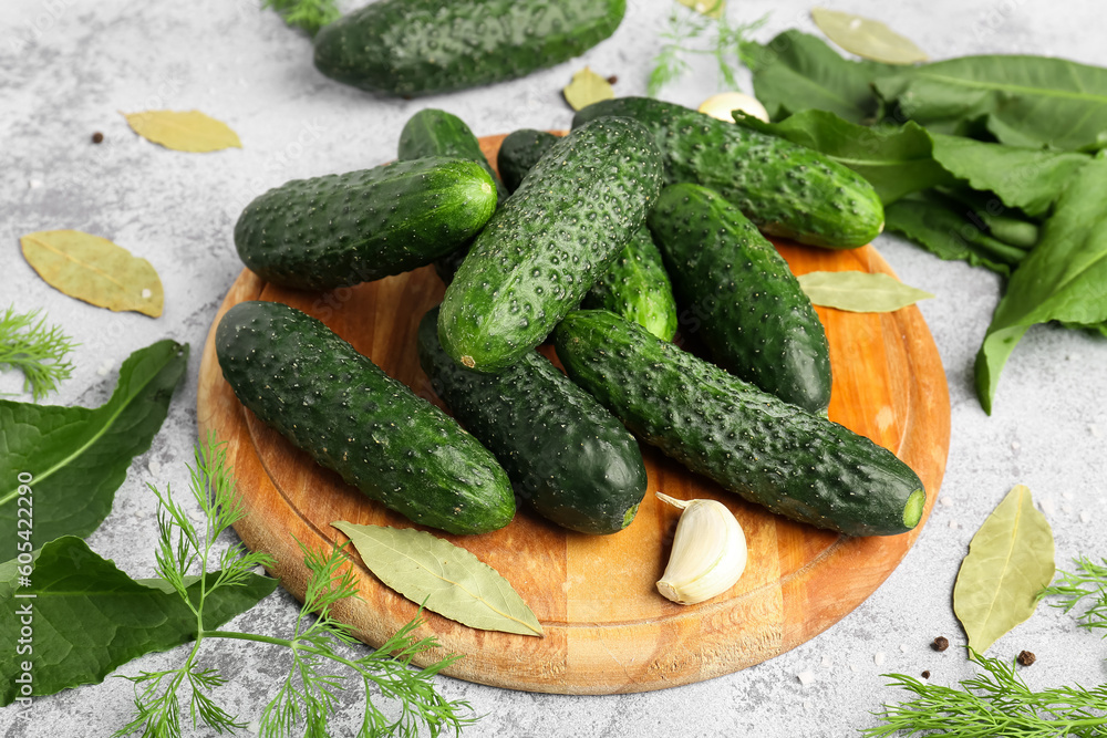 Wooden board with fresh cucumbers for preservation on light background