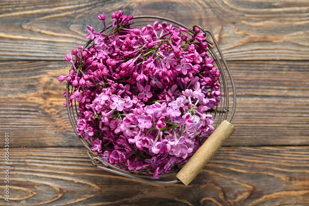 Bucket of beautiful lilac flowers on brown wooden background