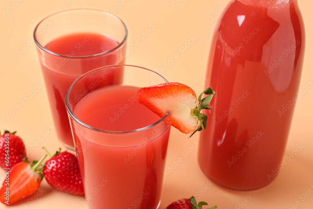 Bottle and glasses of tasty strawberry juice on orange background